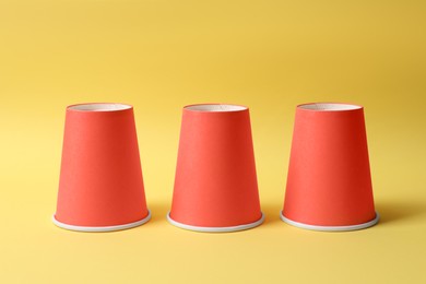 Photo of Three red cups on yellow background. Thimblerig game
