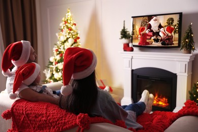Image of Family watching festive movie on TV in room decorated for Christmas 