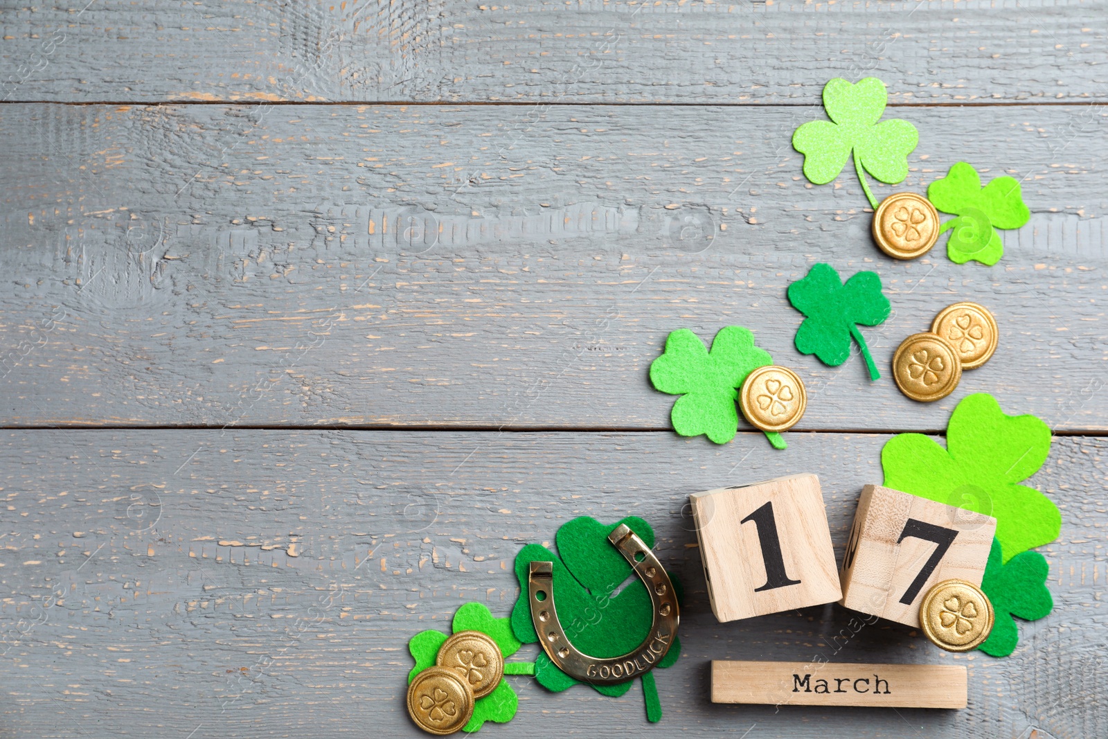 Photo of Flat lay composition with horseshoe and block calendar on grey wooden background, space for text. St. Patrick's Day celebration