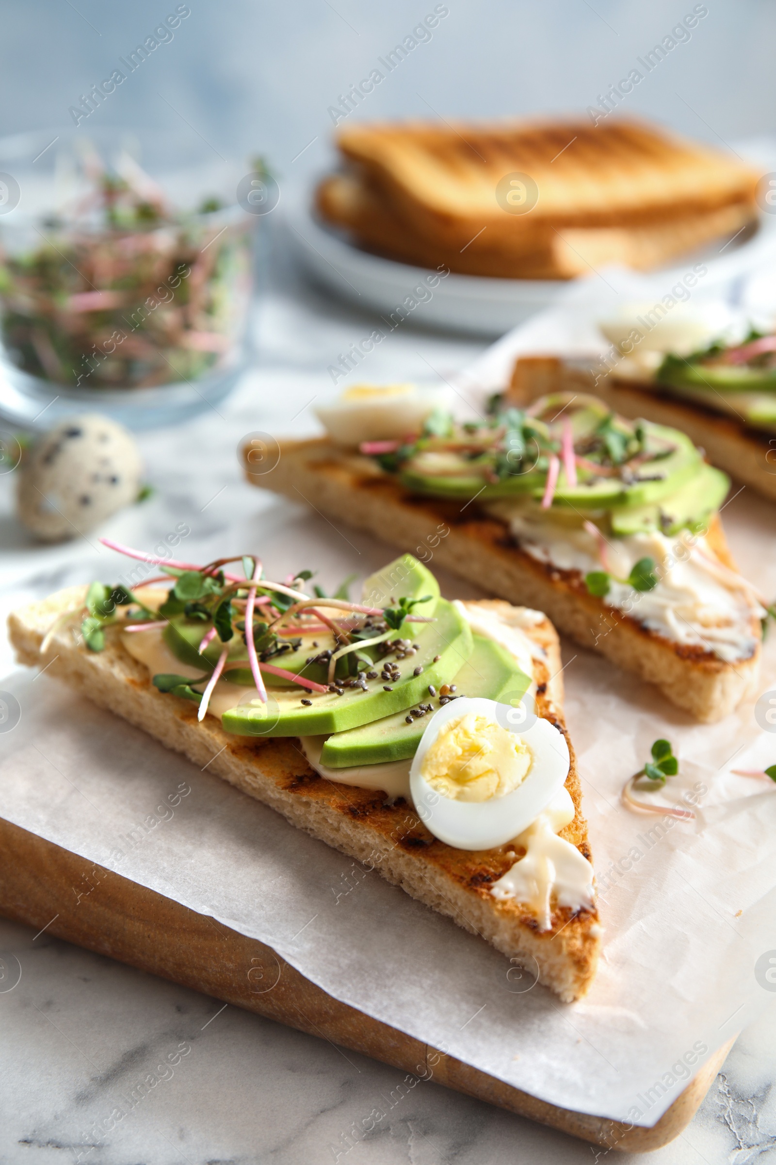 Photo of Tasty toasts with avocado, quail egg and chia seeds served on board