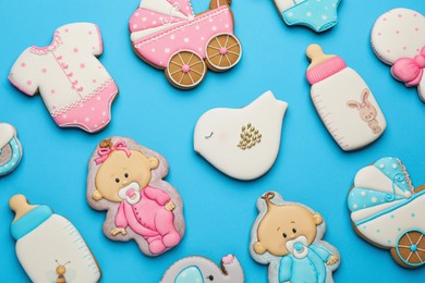 Cute tasty cookies of different shapes on light blue background, flat lay. Baby shower party