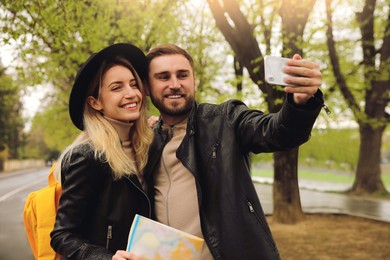 Photo of Couple of tourists with smartphone taking selfie on city street