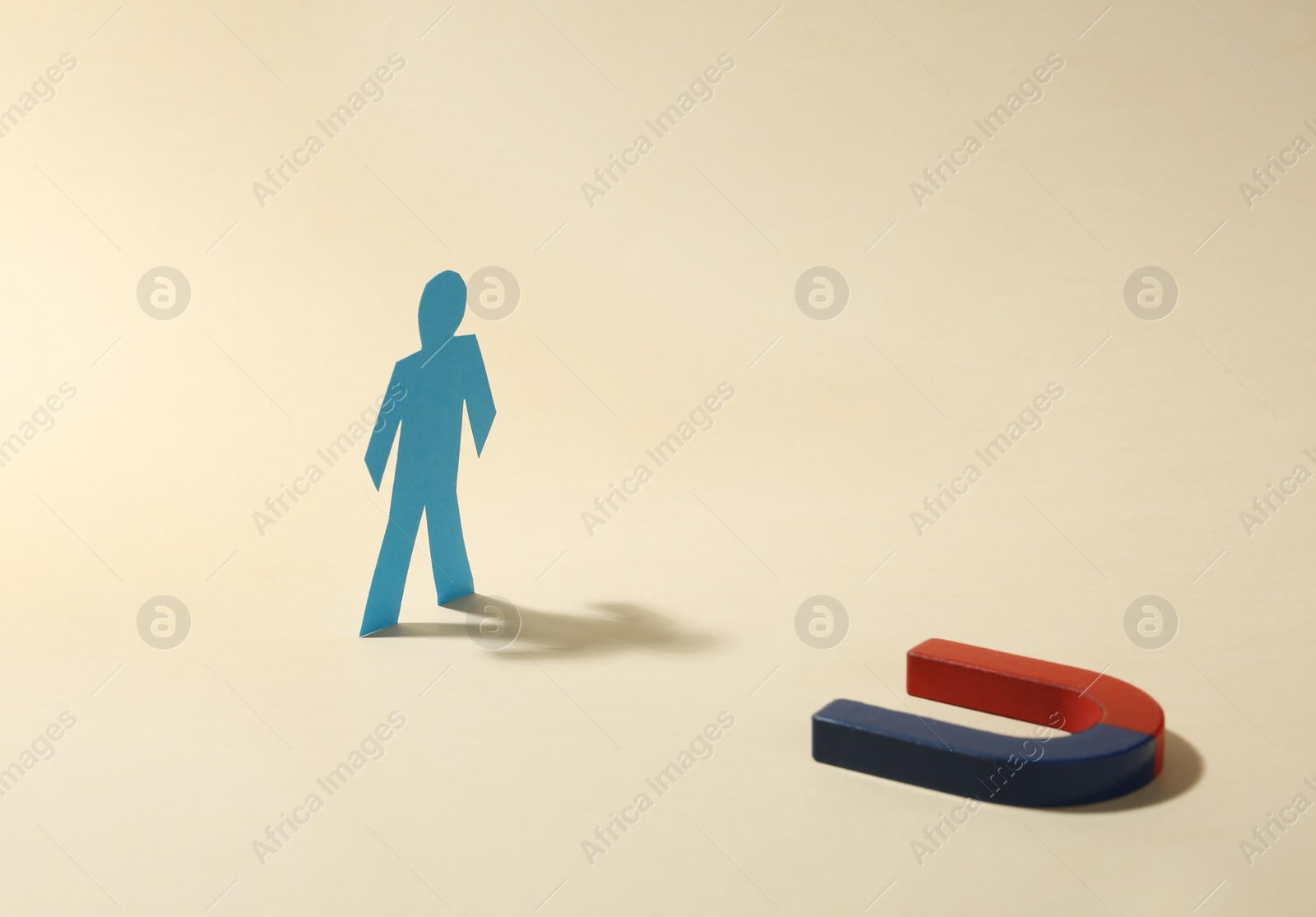 Photo of Magnet attracting paper person on beige background