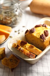 Photo of Delicious pumpkin bread with pecan nuts on tablecloth
