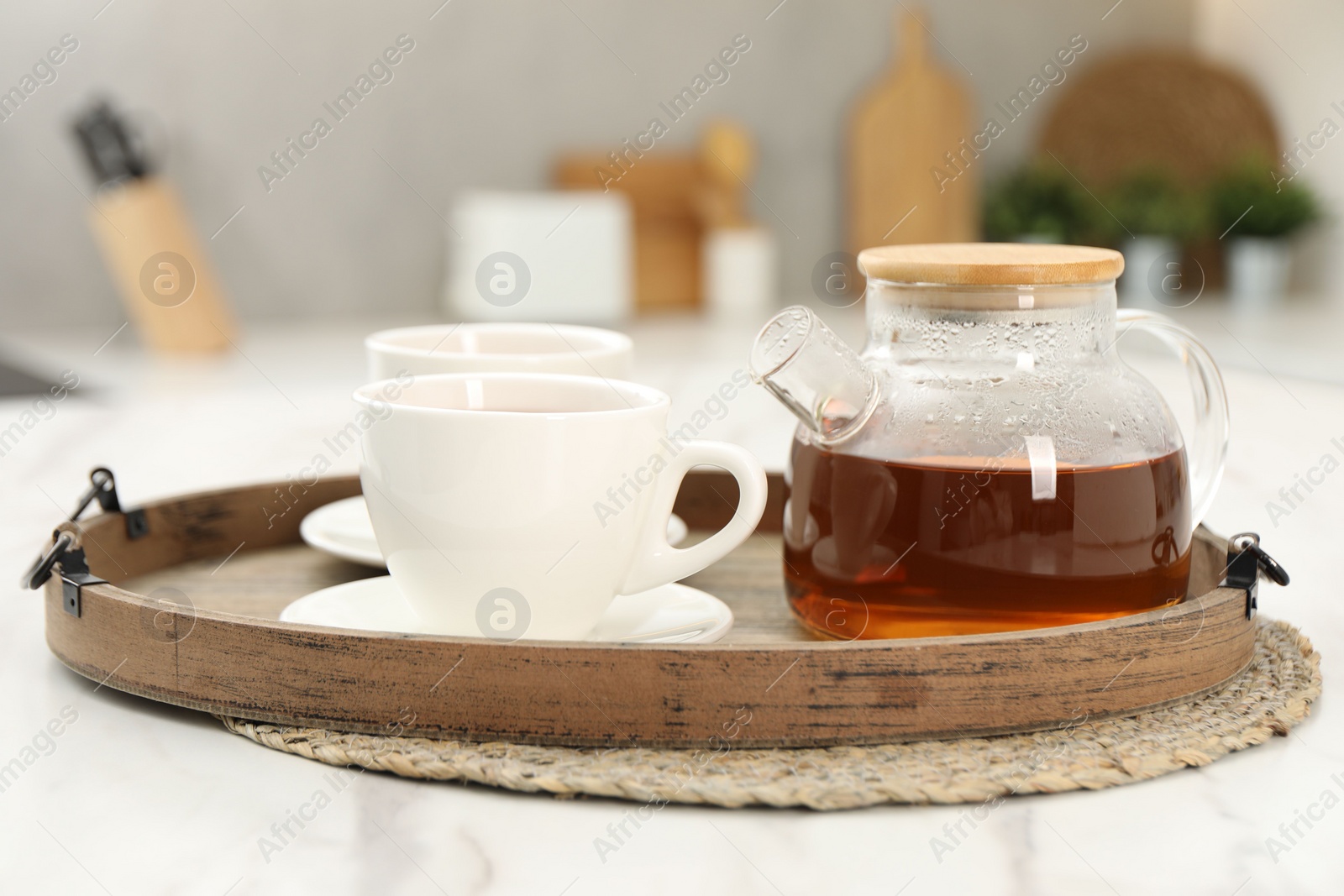 Photo of Aromatic tea in glass teapot and cups on white table