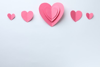 Photo of Pink paper hearts on white background, flat lay. Space for text