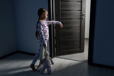 Photo of Girl in pajamas with toy bunny sleepwalking indoors at night