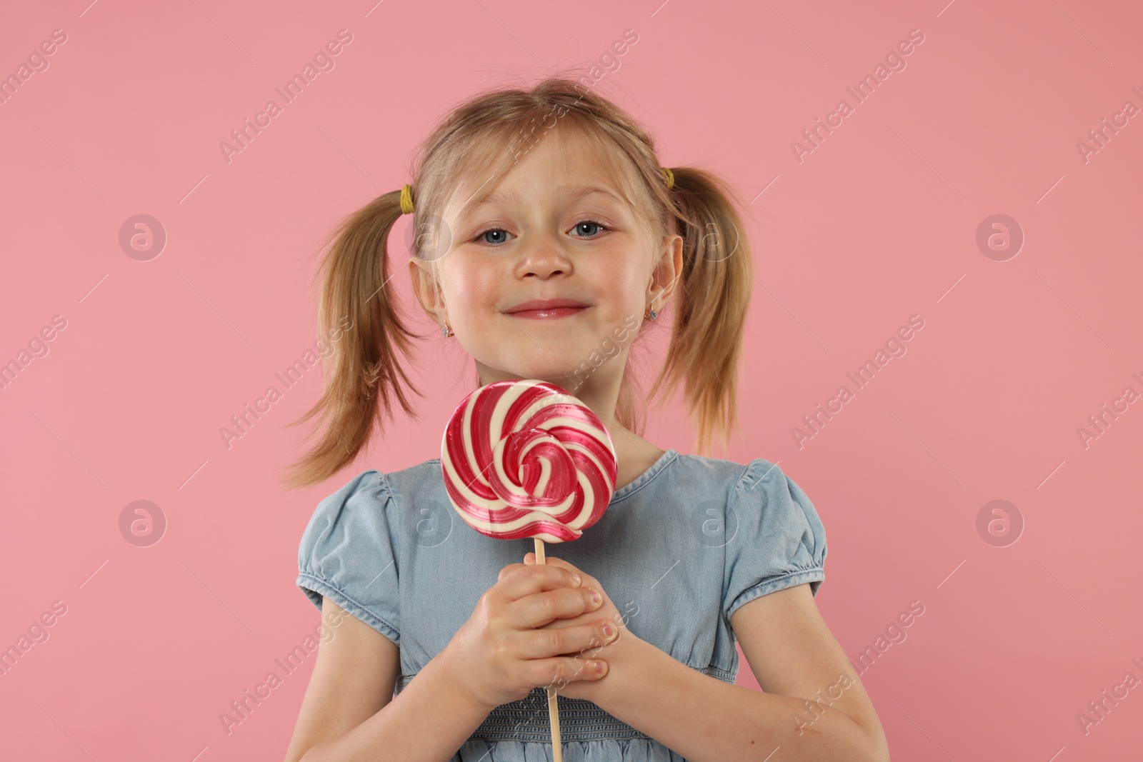 Photo of Portrait of cute girl with lollipop on pink background