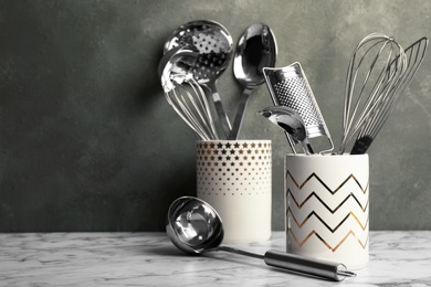 Holder with clean kitchen utensils on table. Space for text