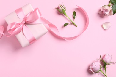 Photo of Gift box and beautiful rose flowers on pink background, flat lay. Space for text