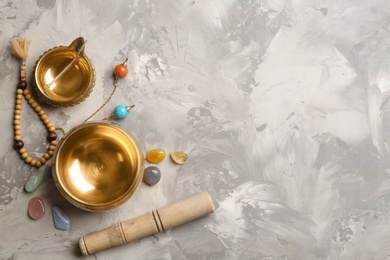 Photo of Flat lay composition with golden singing bowl on grey table, space for text. Sound healing