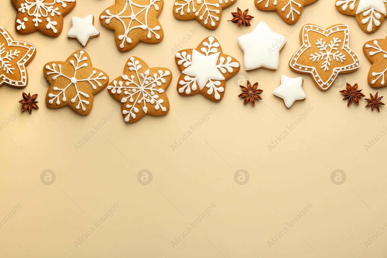 Photo of Tasty Christmas cookies with icing and anise stars on beige background, flat lay. Space for text