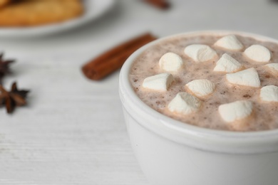 Photo of Delicious hot cocoa drink with marshmallows in cup on white wooden table, closeup