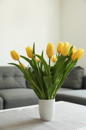 Photo of Bouquet of beautiful yellow tulips on table in living room