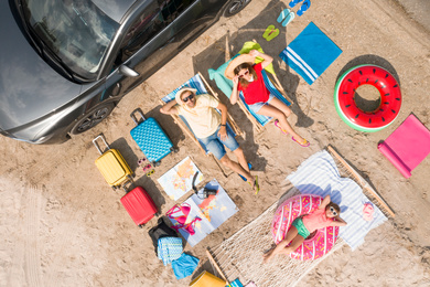 Family with beach accessories and car near river, aerial view. Summer trip