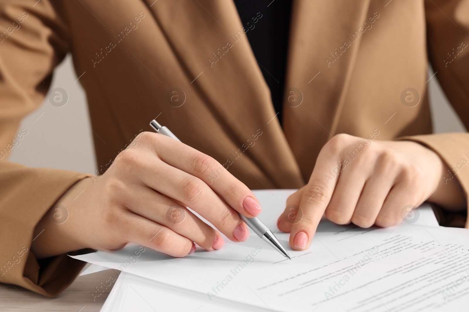 Photo of Woman signing document at table, closeup view