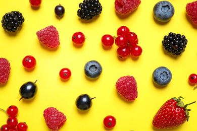 Photo of Mix of fresh berries on yellow background, flat lay