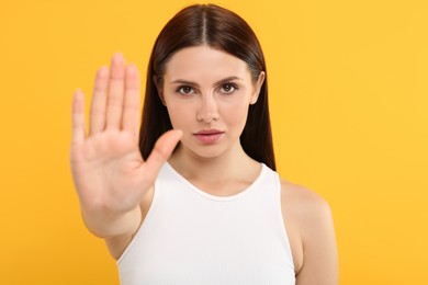 Photo of Woman showing stop gesture on orange background
