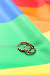 Wedding rings on rainbow LGBT flag, closeup