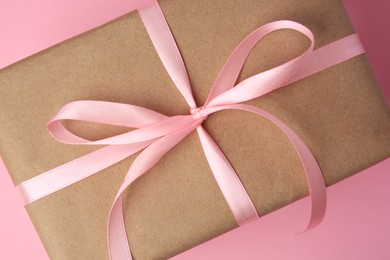 Photo of Beautiful gift box with bow on pink background, top view