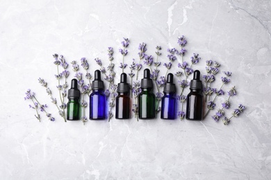 Flat lay composition with bottles of natural lavender essential oil on grey stone background