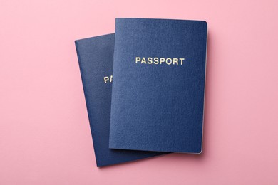 Photo of Blank blue passports on pink background, flat lay