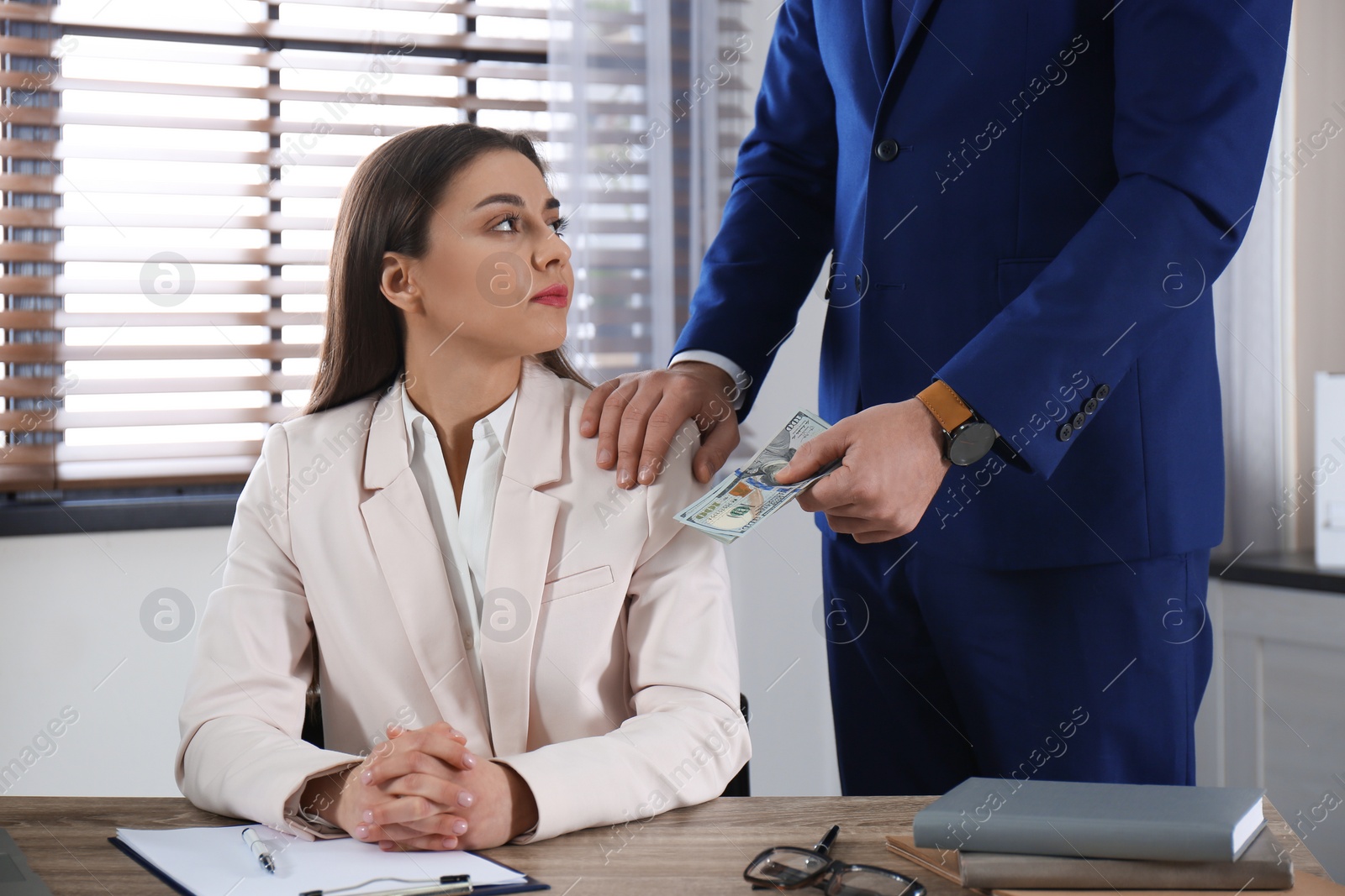 Photo of Man giving bribe to woman at table in office