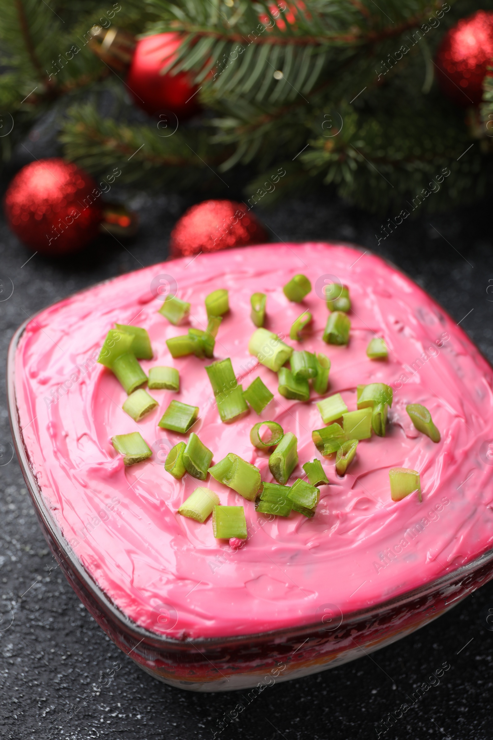 Photo of Herring under fur coat salad and Christmas decor on grey table, closeup. Traditional Russian dish