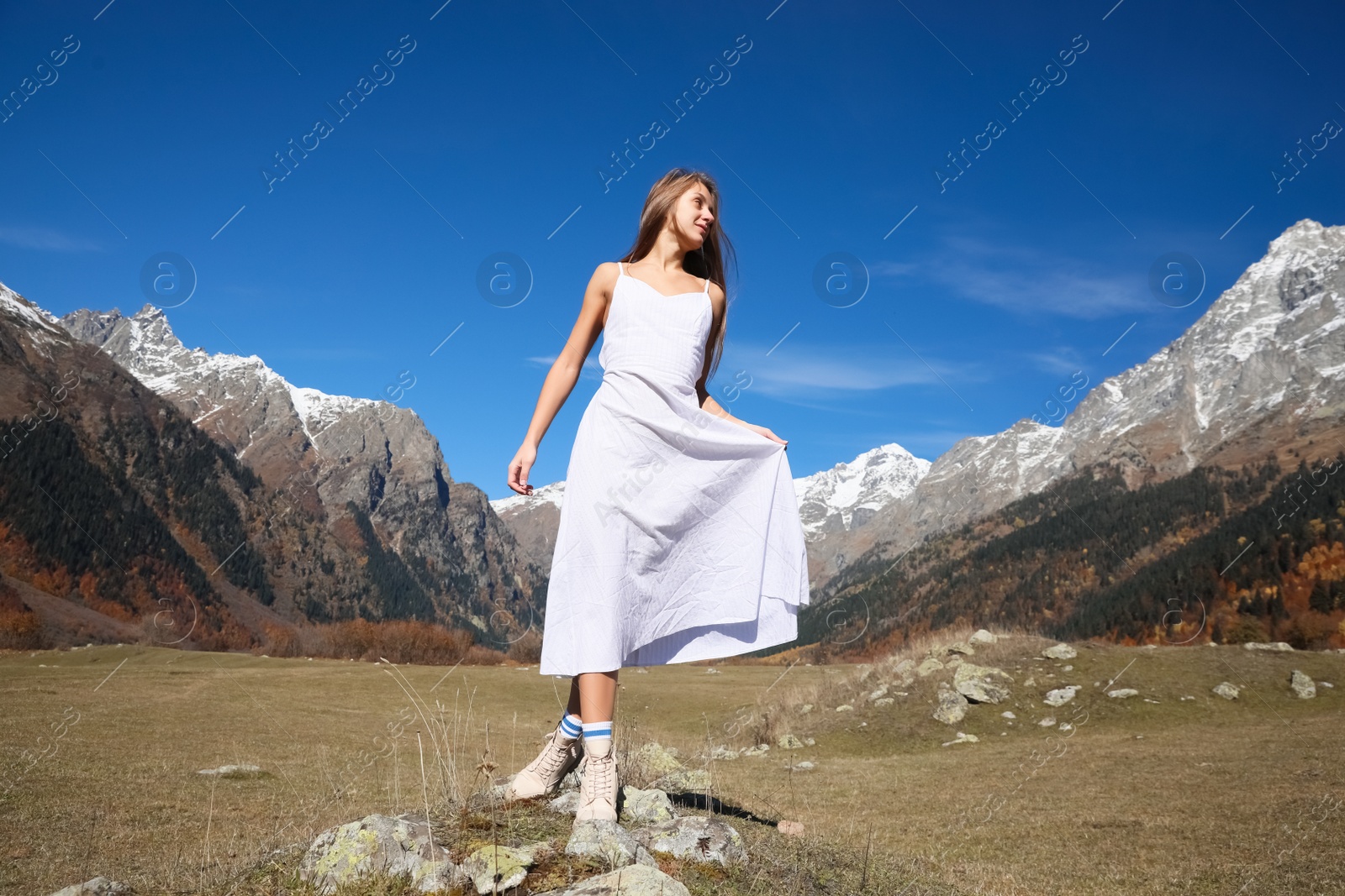 Photo of Young woman walking in beautiful mountains on sunny day, low angle view