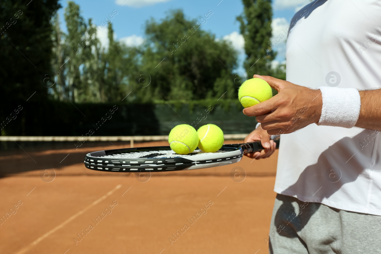 Photo of Sportsman with racket and tennis balls at court, closeup