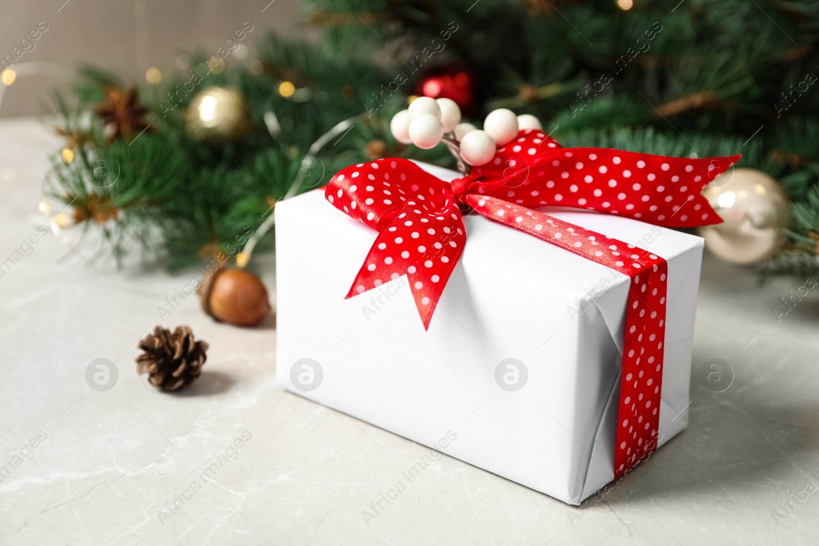 Photo of Christmas gift box with red bow and festive decor on light table