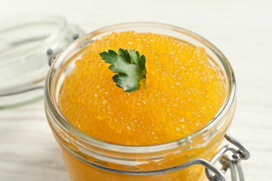 Photo of Fresh pike caviar and parsley in glass jar on table, closeup