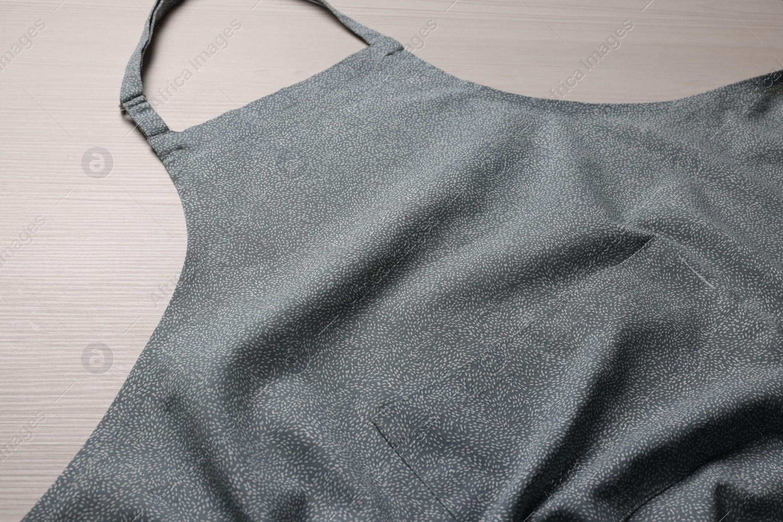 Photo of Stylish apron on white wooden table, closeup. Mockup for design