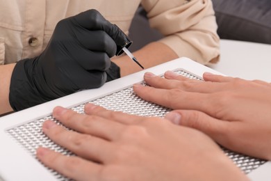 Professional manicurist working with client at table, closeup