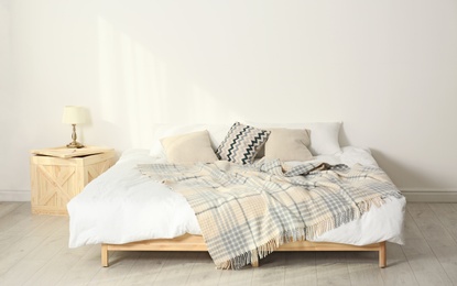 Photo of Bed with pillows and plaid in modern room interior