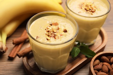 Photo of Tasty banana smoothie with almond and cinnamon on wooden table, closeup