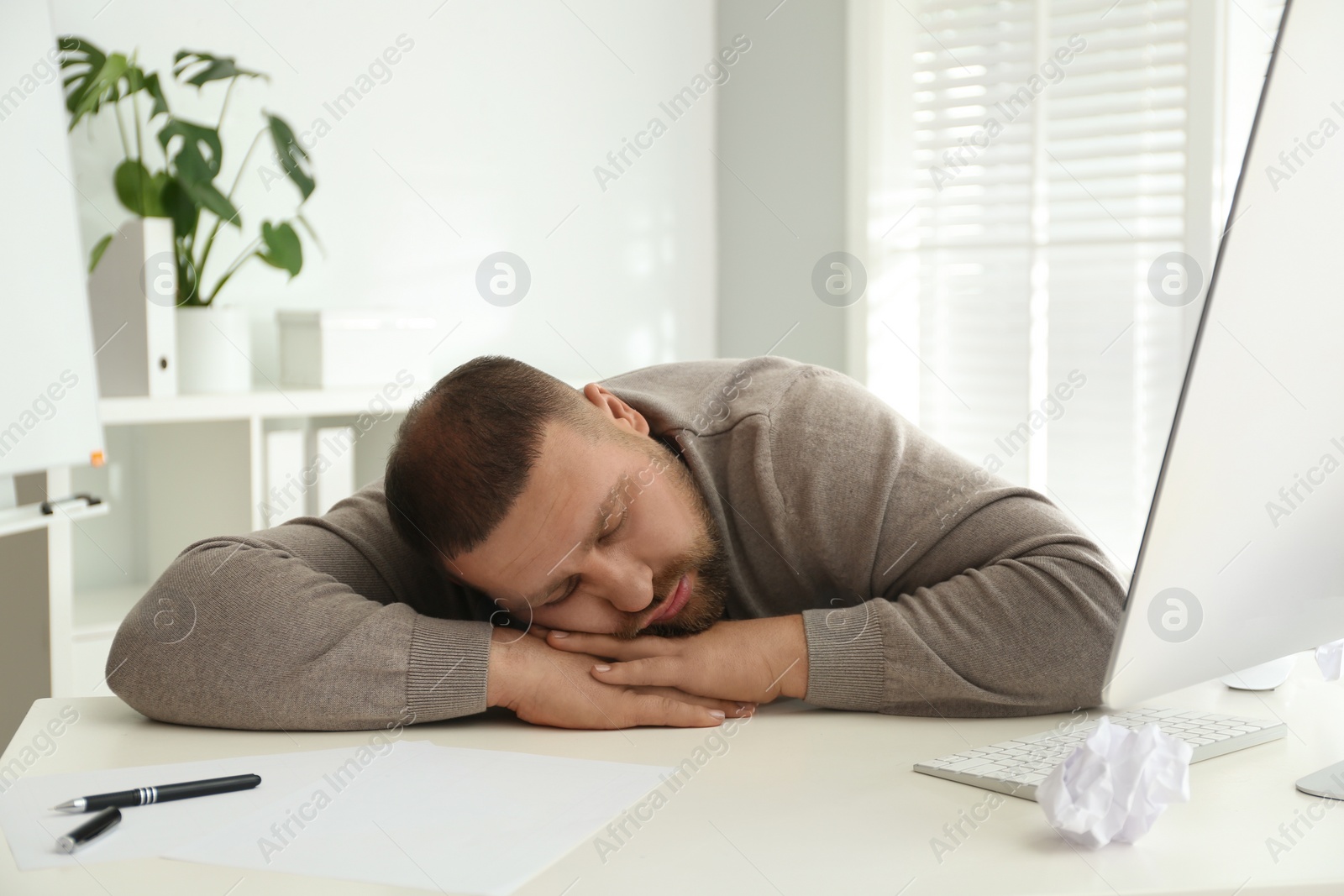 Photo of Lazy overweight office employee sleeping at workplace