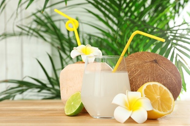 Photo of Composition with glass of coconut water on wooden table against blurred background
