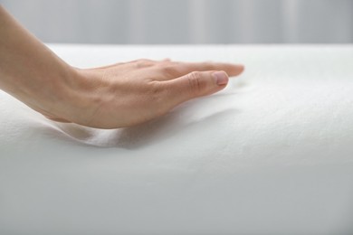 Woman with orthopedic memory foam pillow on white background, closeup