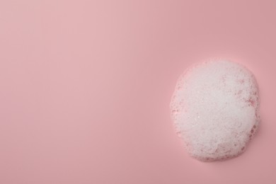 Photo of Drop of fluffy soap foam on pink background, top view. Space for text