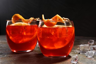 Photo of Aperol spritz cocktail, ice cubes and orange slices in glasses on grey textured table, closeup