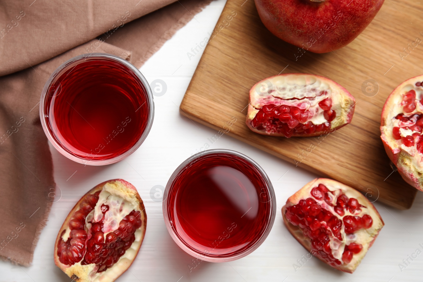 Photo of Glasses of pomegranate juice and fresh fruits on white wooden table, flat lay