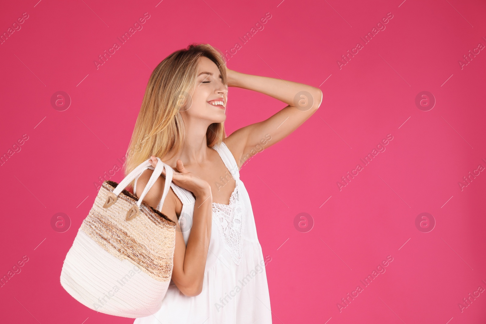 Photo of Beautiful young woman with stylish straw bag on pink background. Space for text