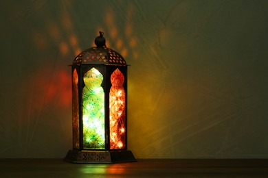 Decorative Arabic lantern on table against dark background. Space for text