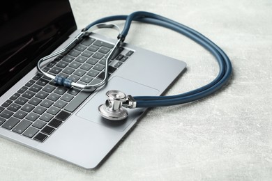 Photo of Stethoscope and modern laptop on grey table