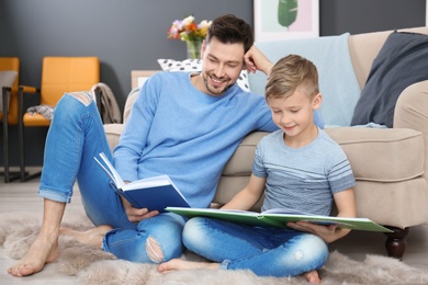Photo of Little boy and his dad reading books at home
