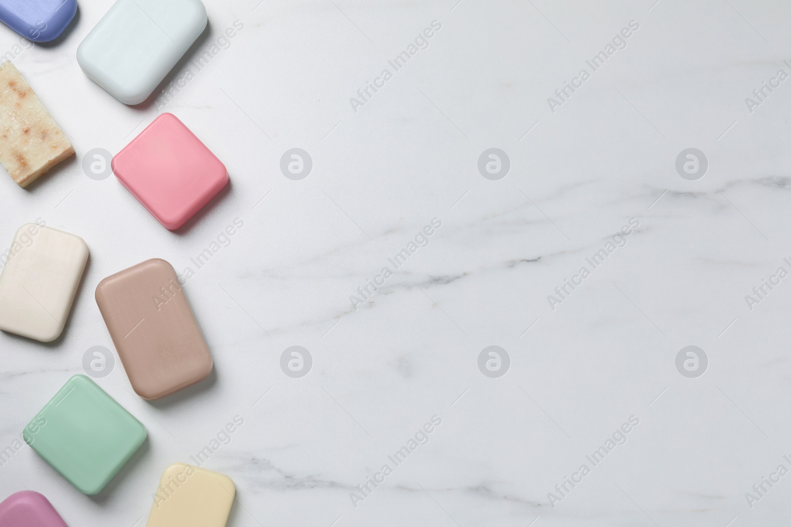 Photo of Many different soap bars on white marble table, flat lay. Space for text