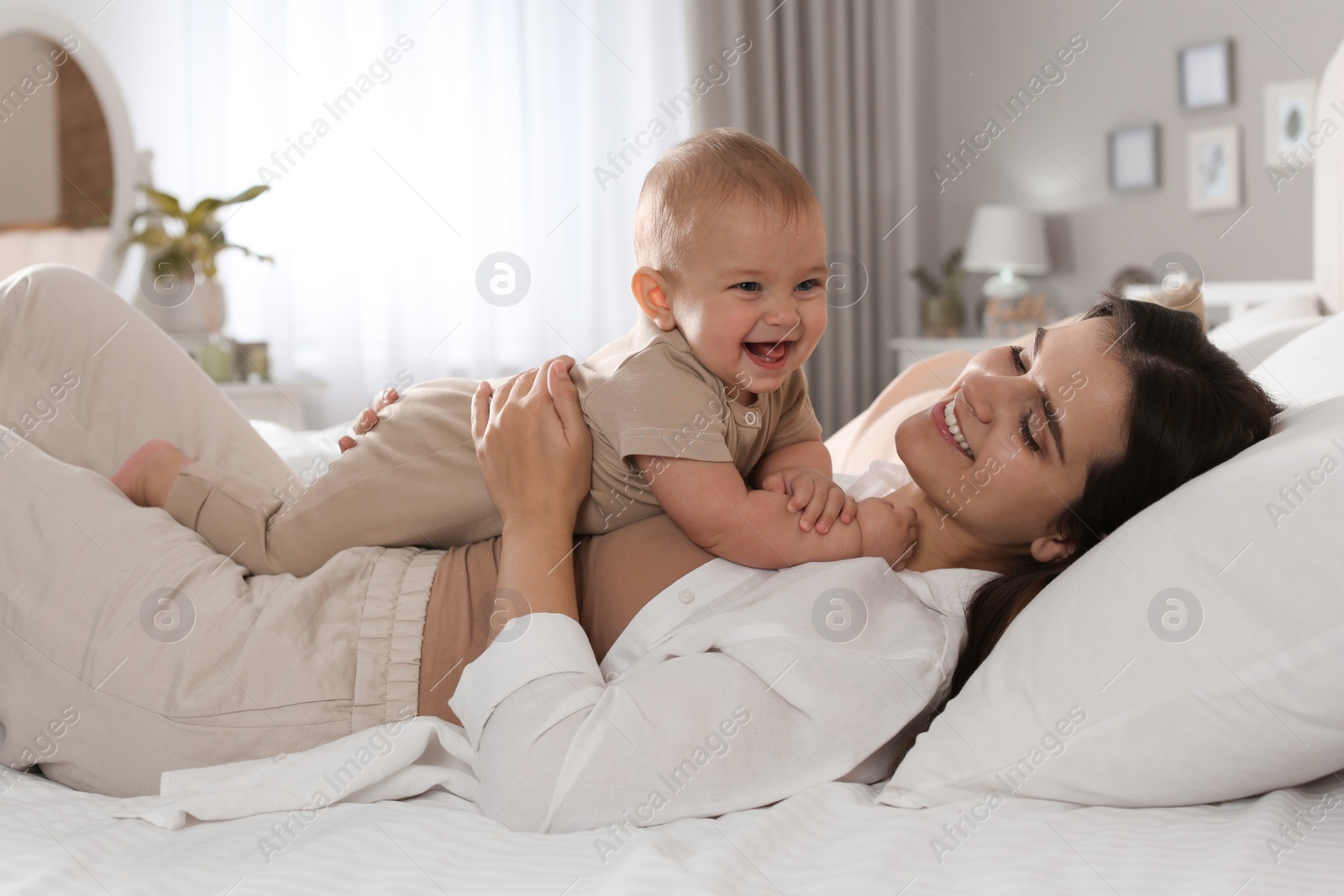 Photo of Happy young mother with her cute baby on bed at home