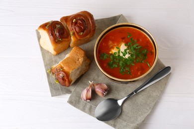 Photo of Delicious borsch served with pampushky on white wooden table, above view. Traditional Ukrainian cuisine