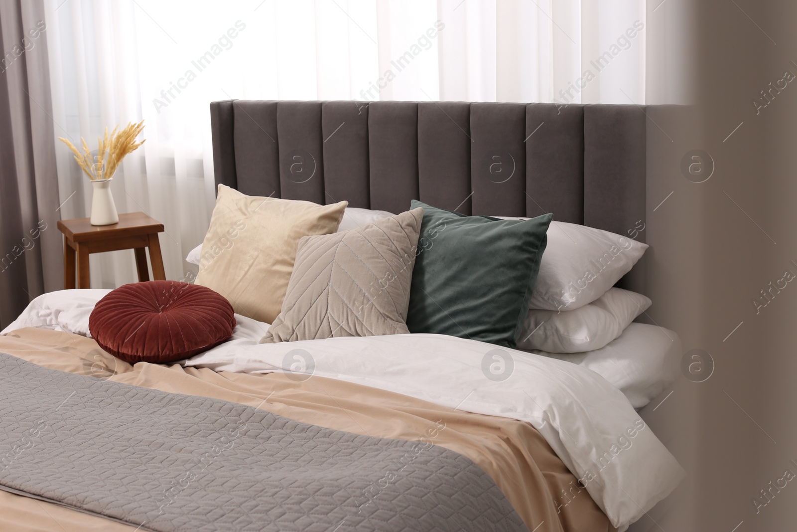 Photo of Large comfortable bed with soft pillows and duvet in room. Home textile